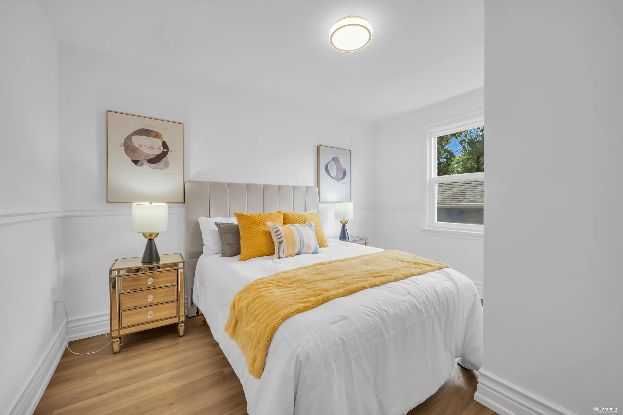 The main-floor bedroom with a window on the side wall and a panelled headboard