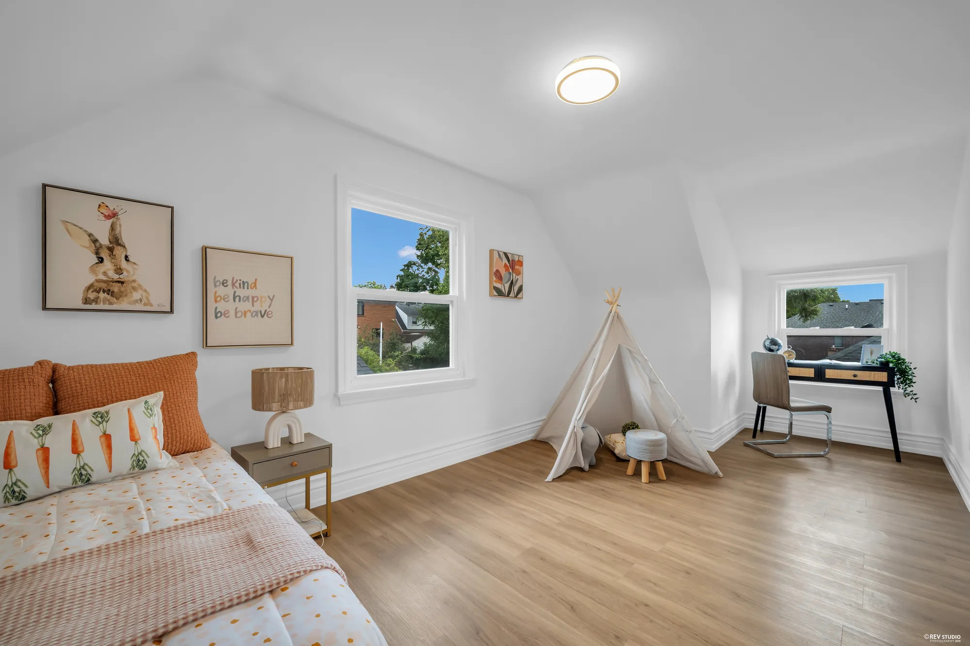 The first upstairs bedroom with a sloped ceiling, two windows and a desk in the corner