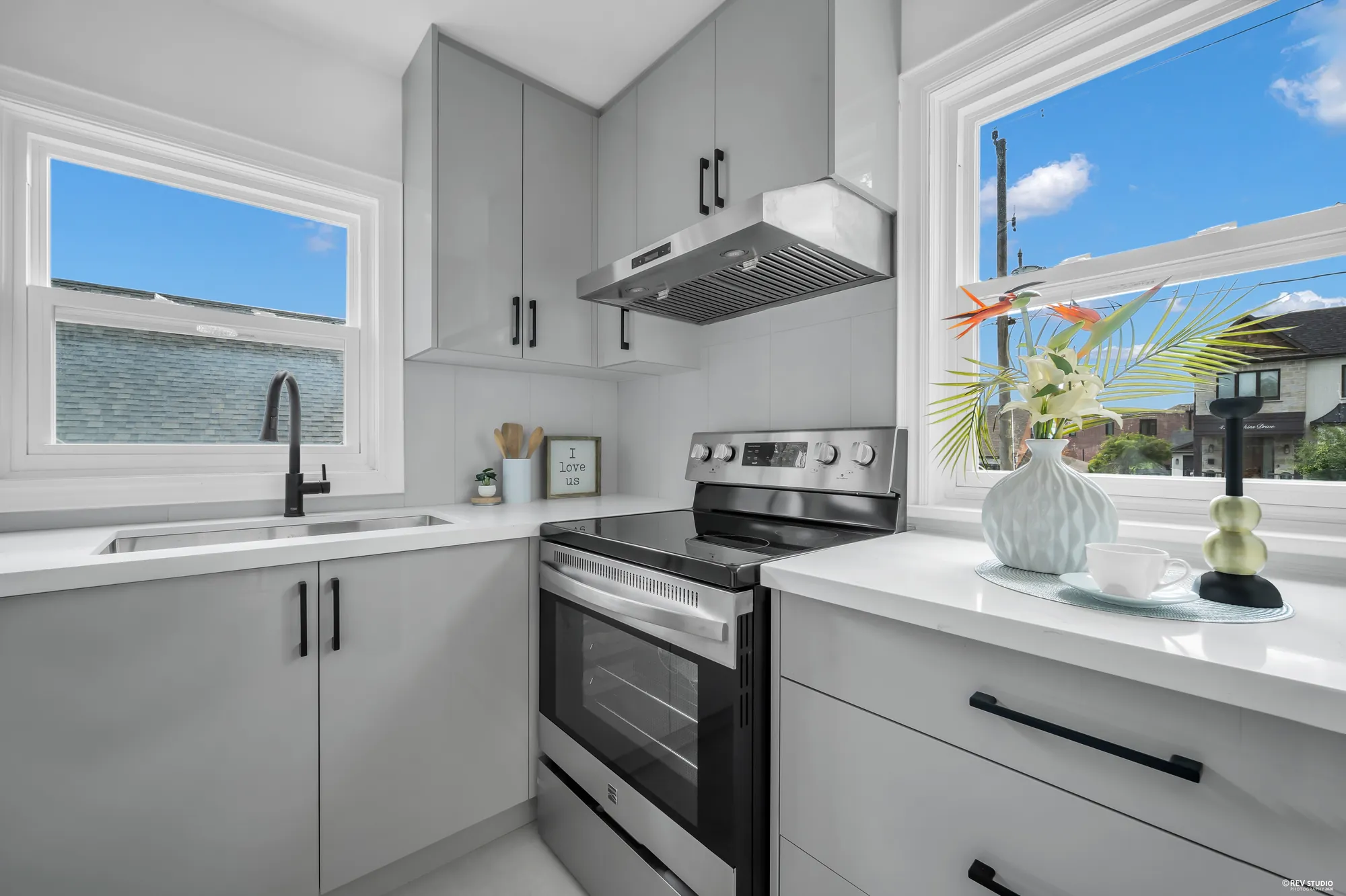 The kitchen with white cabinets, a stainless range and a window over the sink