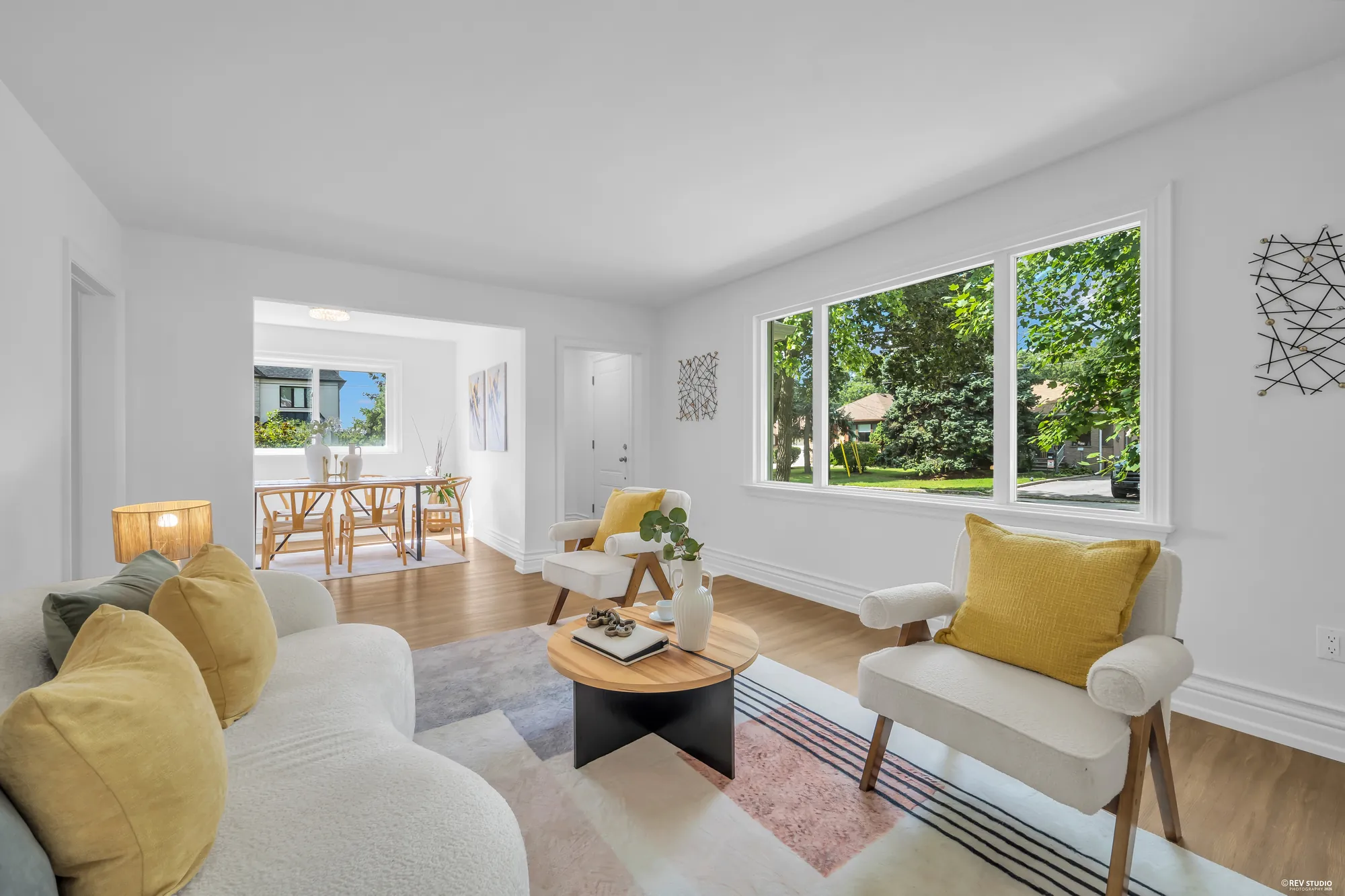 The living room with a picture window at the front and an opening through to the dining room