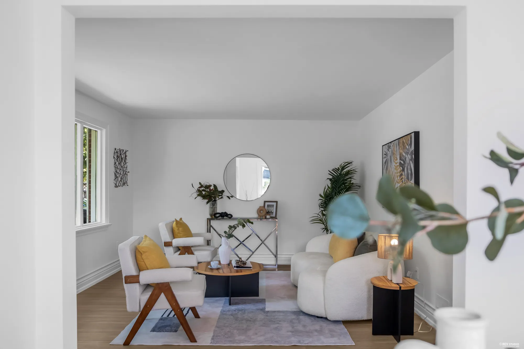 The living room seating area with a round mirror above the console table