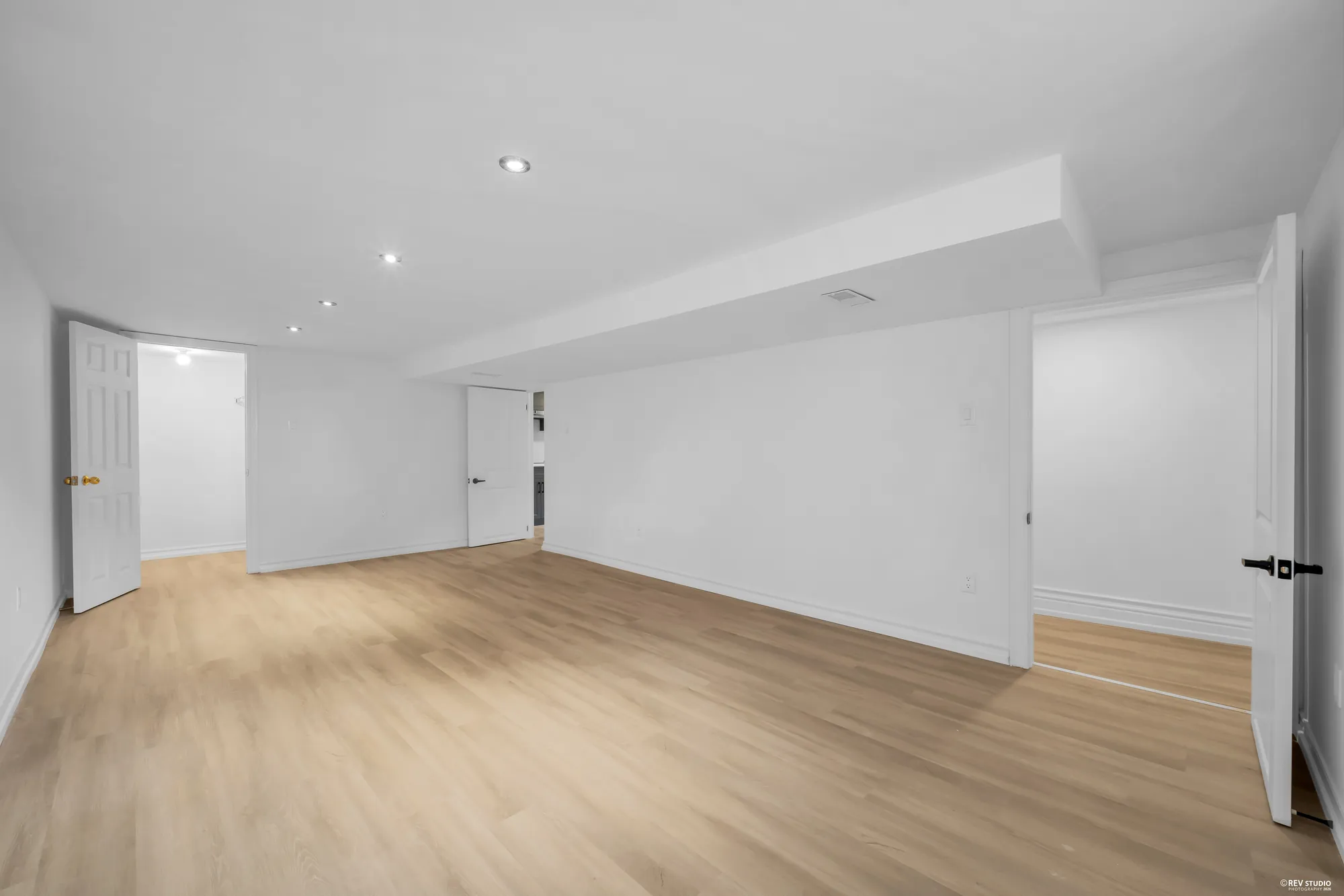 The open room on the lower level with plank flooring and pot lights