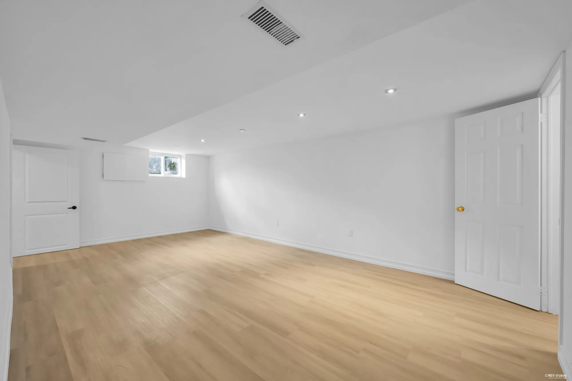 The lower-level open room from the other end, with a window near the ceiling