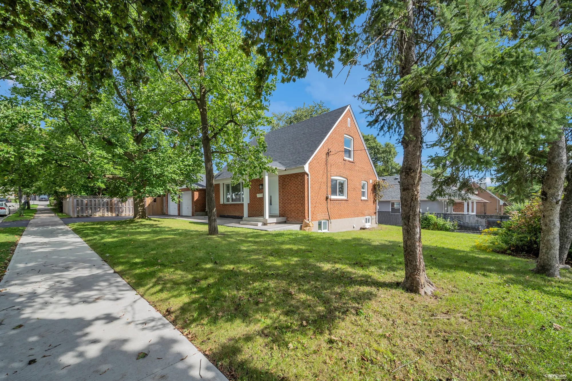 The house from the sidewalk, brick with a dormer window above